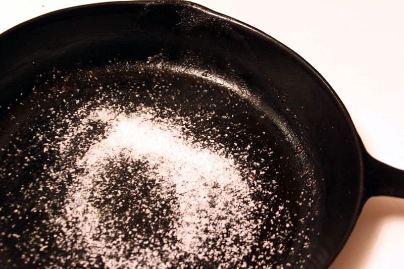 Чтобы не брызгало масло на сковороде. Соль на сковороде. Прокалка чугунной сковороды с солью. Прокалить сковороду с солью. Соль почернела на сковороде.